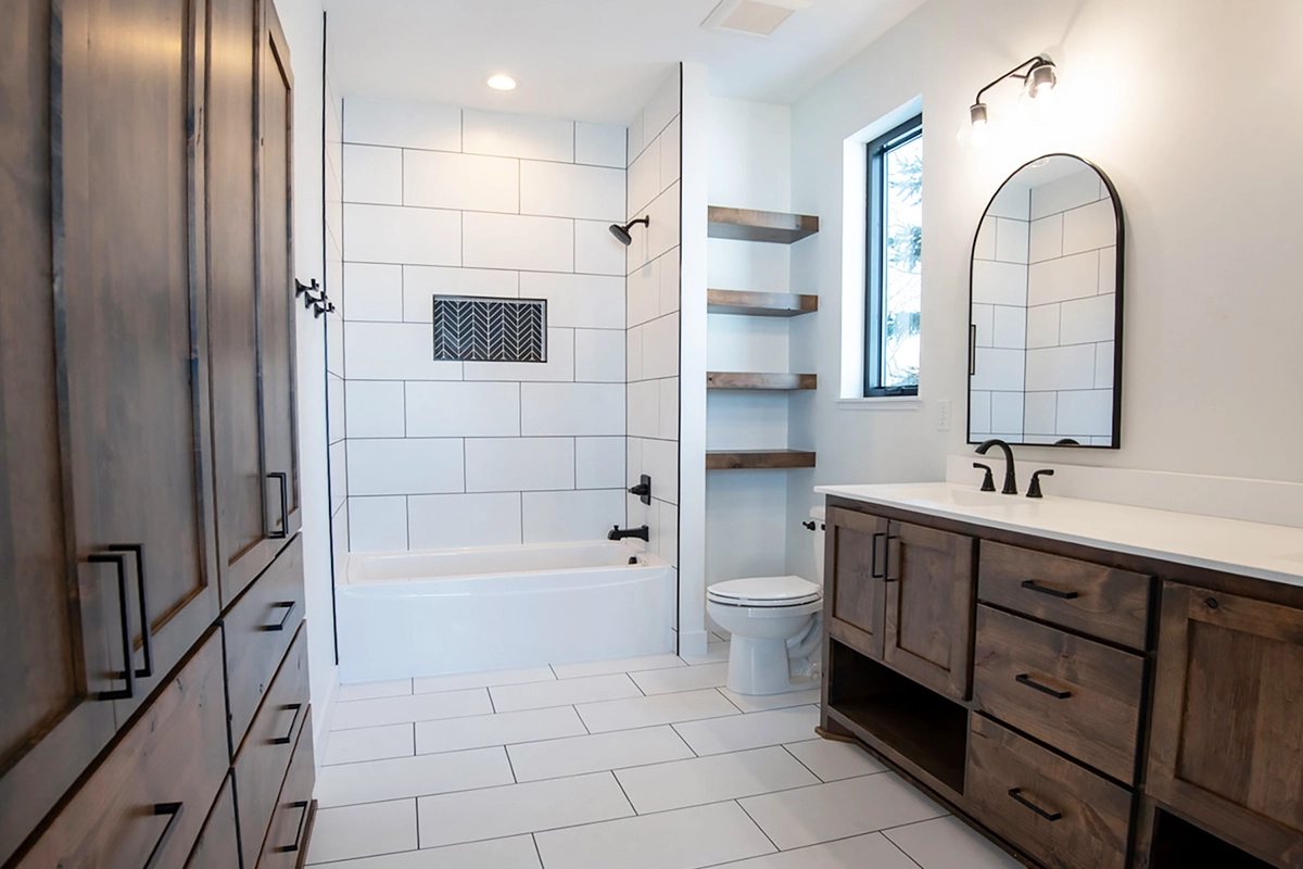 Zimmerman MN bathroom renovation featuring rustic oak cabinetry, a white subway tile soaking tub surround, and a mosaic niche