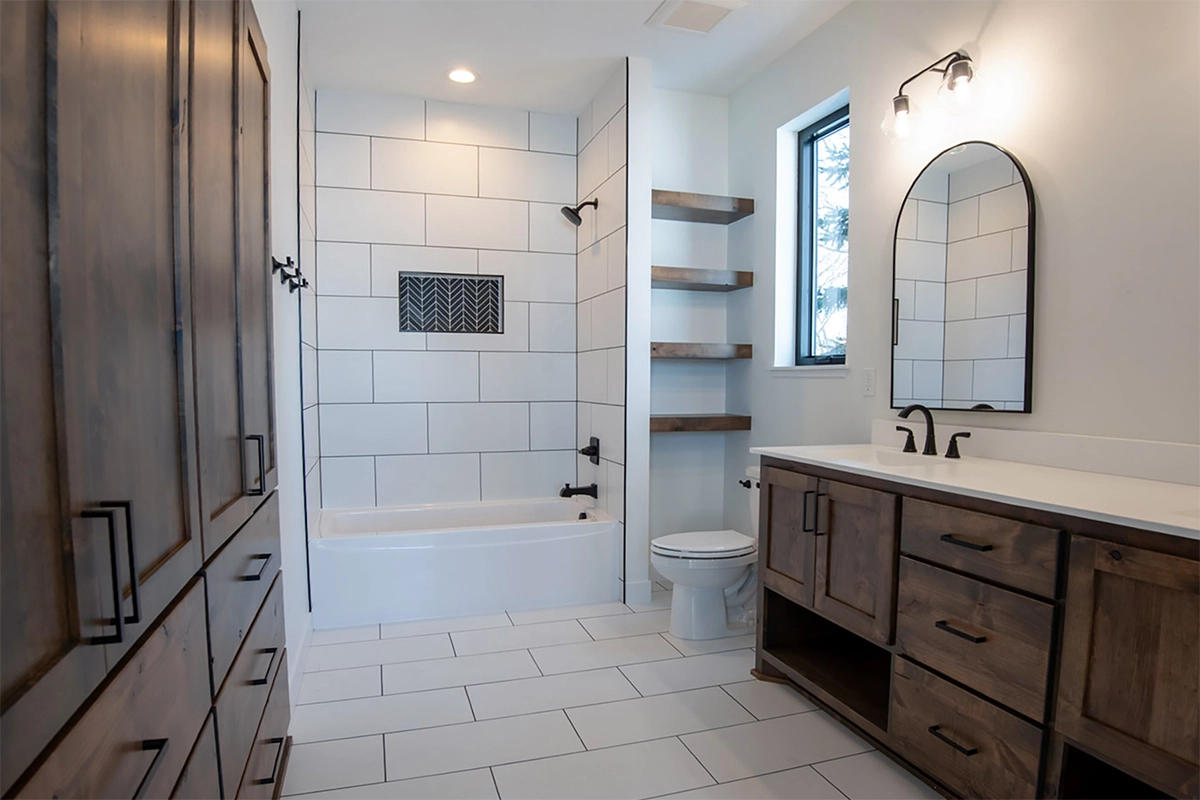 Zimmerman bathroom remodel with rustic cabinets, modern white tile tub surround, decorative niche, and soaking tub